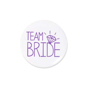 Close-up of white Team Bride tinplate badge with purple lettering and diamond ring icon
