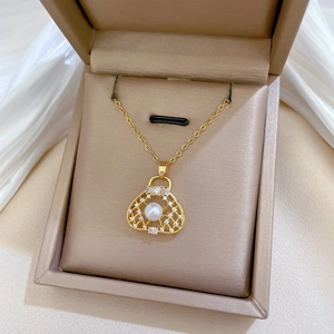 Detail of luxury gold handbag pendant with pearls and diamonds on white silk