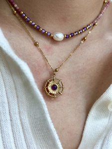 Detail of layered gold necklace with amethyst pendant, baroque pearl and purple beads