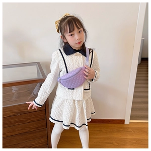 Close-up of a purple quilted leather chest bag for kids worn with a white dress