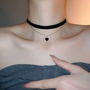 Detail of double-layer choker featuring black velvet ribbon and gold heart pendant necklace