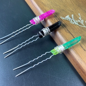 Detailed view of three U-shaped hair pins with pink, black, and green crystal points