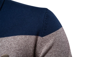 Nahaufnahme des Strickpullovers mit Patchwork-Muster, Nähten und Metall-Logo-Etikett
