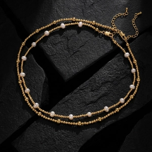 Close-up of double-layered gold bead and freshwater pearl necklace on black stone