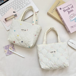 Close-up of quilted canvas bags featuring colorful heart and rabbit embroidery motifs