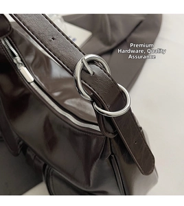 Detailed view of silver metal buckle and shiny coffee PU leather on shoulder bag