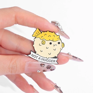 Cartoon pufferfish enamel pin with 'NOT A HUGGER' banner and yellow prickly texture