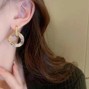 Detailed close-up of a gold geometric crystal hoop earring worn by a model in soft light