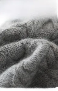Close-up of grey cable knit texture showing premium soft wool fabric and stitching details