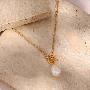 Macro detail of gold-plated square link chain with white baroque pearl and OT toggle clasp