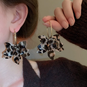 Close-up of vintage leopard print resin flower hoop earrings worn by a model