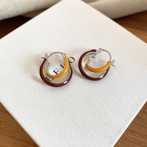 Detail of cross hoop earrings with burgundy and ginger enamel on white jewelry box