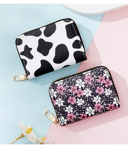 Detail view of cow print and floral PU leather accordion wallets with golden zippers