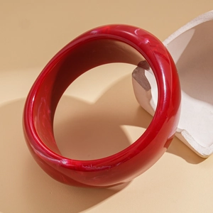 Artistic detail of a red marble-patterned acrylic resin bangle on a warm-toned background