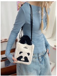 Close-up of a plush panda crossbody bag with black handles on a female model