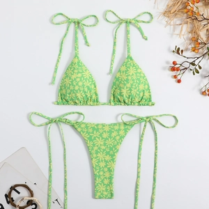 Detailed flat lay of floral print bikini set with straw and magazine on white background