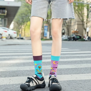 Close-up of asymmetric mid-calf cotton socks with colorful mushroom and star patterns