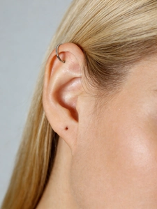 Close-up of a minimalist silver C-shaped ear cuff worn on the cartilage ear bone