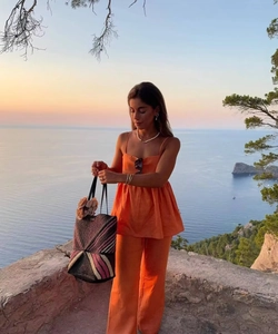 Ensemble de vacances orange avec caraco et pantalon large accompagné d'un sac de plage