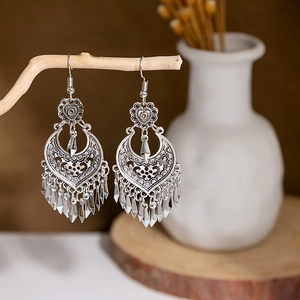 Bohemian vintage hollow heart and crescent earrings with metallic tassels on a branch