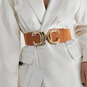 Detail of tan wide elastic belt with gold interlocking CC buckle on a white blazer