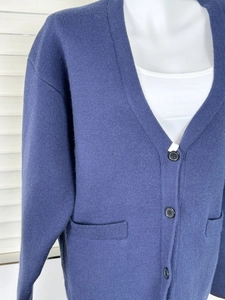 Detail of blue knit cardigan featuring V-neckline, resin buttons and side pockets