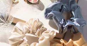 Detailed macro view of beige, grey and brown satin silk scrunchies with soft pleats