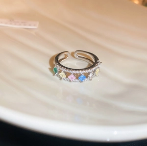 Macro shot of silver adjustable ring featuring five colorful gemstones with diamond accents