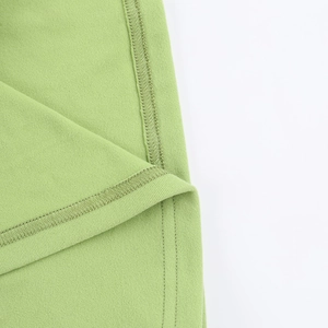 Détail macro de la texture du tricot vert herbe et coutures de qualité sur la robe