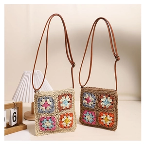 Close-up of handmade crochet crossbody bags with colorful floral patterns and leather straps