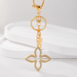 Golden sparkling clover keychain charm with crystal diamonds on geometric stand