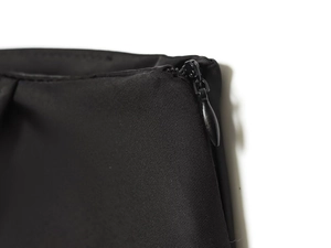 Close-up of black woven fabric texture with hidden zipper detail on asymmetric lace skirt