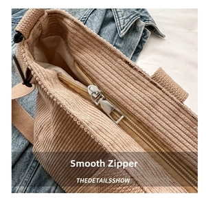 Detailed close-up of smooth silver metal zipper on light brown corduroy tote bag