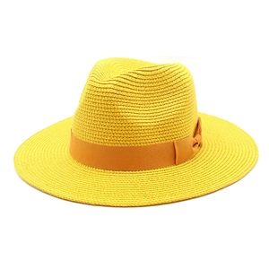 Close-up of bright yellow woven straw hat featuring a chic orange ribbon and bow detail