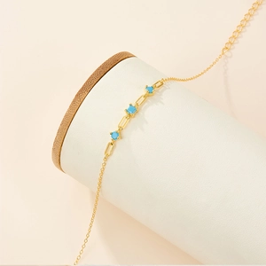 Detailed shot of golden link bracelet with blue turquoise stones on white jewelry display