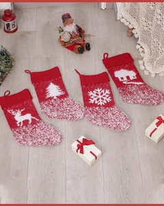 Set of four red knitted Christmas stockings with reindeer and snowflake patterns on wood