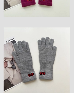 Close-up of knit gloves featuring ribbed cuffs and decorative red bow embroidery details