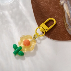 Close-up of a cute yellow tulip flower keychain with green leaves and a golden metal clasp