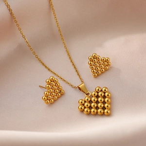 Parure bijoux coeur doré avec collier et boucles d'oreilles sur fond en soie rose doux
