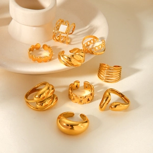 Collection of nine gold plated irregular geometric stainless steel rings on a ceramic base