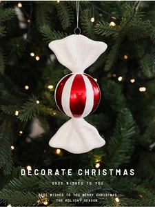 Detail of red and white striped candy ornament with glitter hanging on a Christmas tree