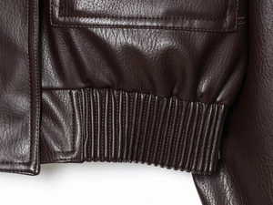 Detail shot of the elastic hem on a dark brown PU leather jacket showing stitching