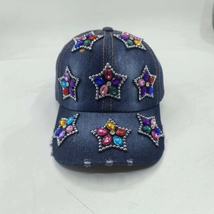Detail der blauen Jeans-Basecap mit bunten Strass-Stern-Patches und ausgefranster Krempe