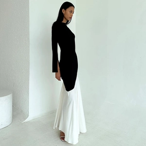 Detail view of the elegant black long sleeves and white pleated skirt of the dress