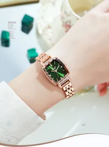 Detail of emerald green sunburst dial and rose gold metal mesh band on a women's watch