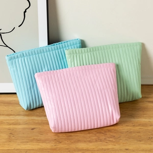 Detailed view of quilted waterproof cosmetic bags in pastel pink, blue, and mint green