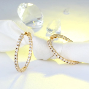 Detailed view of pavé hoop earrings with white zircons on a white satin ribbon
