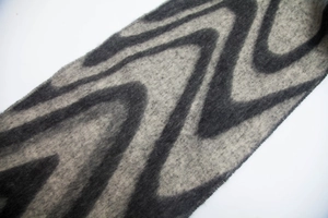 Close-up of thick faux mohair scarf with grey black wave patterns and fringe texture