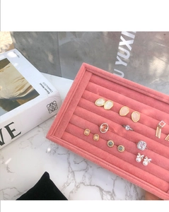 Plateau bijoux en velours rose sur marbre avec boucles d'oreilles et bagues serties