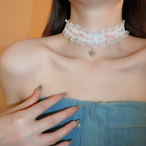 Detail of lace choker with pink ribbon bows and a sparkling heart-shaped pendant on neck